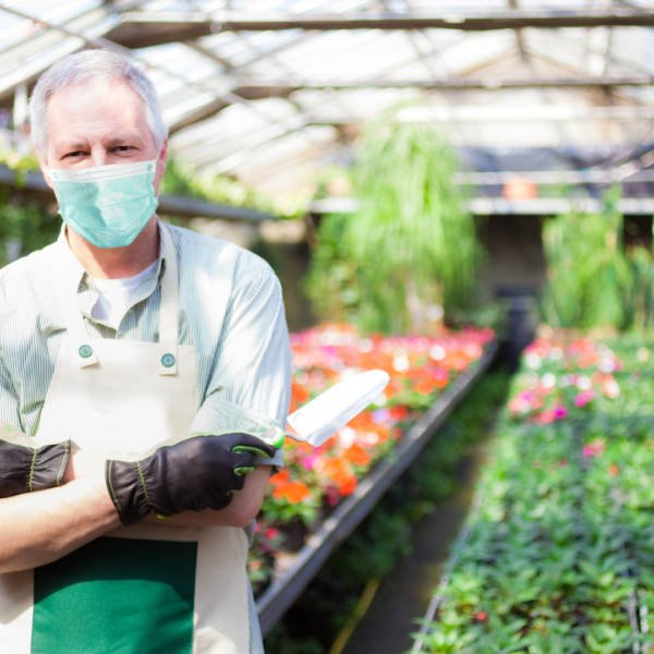 a man in a face mask standing in a green house