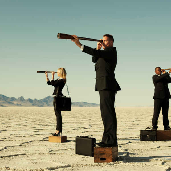 business men and women standing on a beach with telescopes